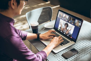 Asian businessman working while attending online meeting with colleagues through laptop in office. unaltered, wireless technology, video conference, discussion, internet, business, teamwork, covid.