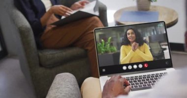 African american man using laptop for video call, with business colleague on screen. Business communication technology and remote home working, digital composite video.