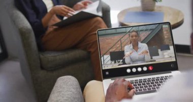 African american man using laptop for video call, with business colleague on screen. Business communication technology and remote home working, digital composite video.