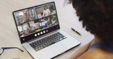 African american woman using laptop for video call, with diverse business colleagues on screen. Business communication technology and remote home working, digital composite video.