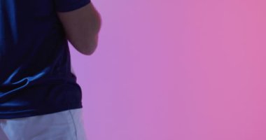 Pembe ışıkta rugby topu taşıyan beyaz erkek rugby oyuncusu. Spor, hareket, eğitim ve aktif yaşam tarzı kavramı.