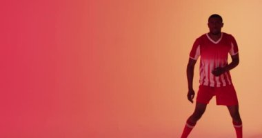 Afrikalı Amerikalı erkek futbolcu neon pembe ışıkta futbolu tekmeliyor. Spor, hareket, eğitim ve aktif yaşam tarzı kavramı.