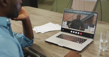 African american man using laptop for video call, with business colleague on screen. Business communication technology and remote home working, digital composite video.