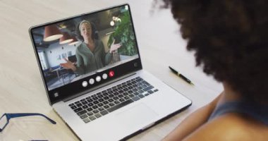 African american woman using laptop for video call, with business colleague on screen. Business communication technology and remote home working, digital composite video.