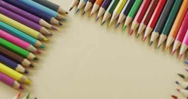 Video of frame with colorful crayons on beige surface with copy space. School equipment, tools, learning and education concept.
