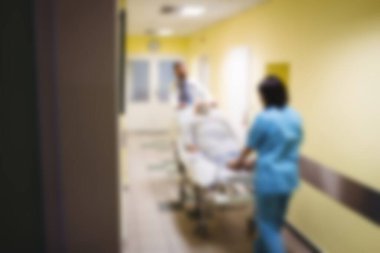 Blurry view of doctor pushing patient in hospital bed through corridor
