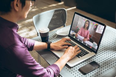 Asyalı iş adamı, iş arkadaşıyla iş görüşmesi yapıyor. Bilgisayarda video görüşmesi yapıyor. değiştirilmemiş, ofis, çevrimiçi, kablosuz teknoloji, video konferansı, internet, iş dünyası, takım çalışması, covid.