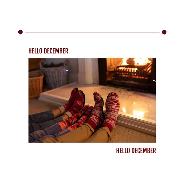 Hello december text over low section of parents with child wearing socks relaxing by fireplace. Digital composite, family, love, togetherness, christmas, winter, holiday and celebration concept.