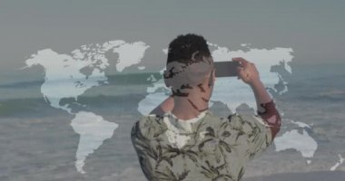 Sahilde akıllı telefonuyla fotoğraf çeken Afrikalı bir Amerikalının dikiz aynasından dünya haritası. dünya fotoğraf günü farkındalık kavramı