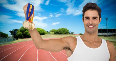 Portrait of smiling man holding medals on running track against sky