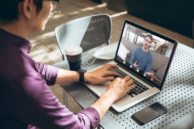 Kafkasyalı iş adamı video konferansı sırasında Asyalı erkek arkadaşa brifing veriyor. değiştirilmemiş, ofis, çevrimiçi, teknoloji, tartışma, İnternet, iş dünyası, takım çalışması, covid.