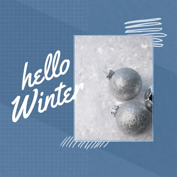 Composite of hello winter text and christmas baubles on snow with grid pattern on blue background. Copy space, christmas, celebration, holiday, greeting, nature, cold temperature and winter concept.