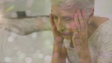 Stresli, Kafkasyalı, yaşlı bir kadının evinde yatakta oturmasına ışık tutuyor. zihinsel sağlık günü farkındalığı kavramı