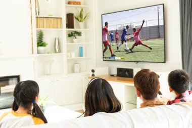 Bir grup çocuk kanepede birlikte oturmuş futbol maçı izliyorlar. Spor, rekabet ve tezahürat.
