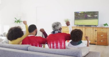 Afro-Amerikan ailenin kanepede oturup evde futbol izlediği bir video. Spor, rekabet ve ailece evde vakit geçirmek..