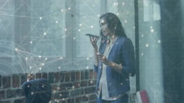 Akıllı telefon kullanan iki ırklı iş kadını üzerinden bağlantı ağının animasyonu. Küresel iş, veri işleme ve bağlantılar konsepti dijital olarak oluşturulmuş video.