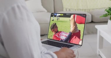 Kafkasyalı bir adamın kanepede oturup dizüstü bilgisayarda futbol izlediği bir video. Spor, rekabet ve ailece evde vakit geçirmek..