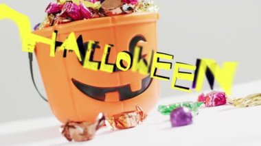 Gri arkaplanda şekerlerle oyulmuş balkabağı kovası üzerine cadılar bayramı metni animasyonu. Cadılar Bayramı, sonbahar, sonbahar, bayram geleneği ve dijital olarak üretilen video konsepti.