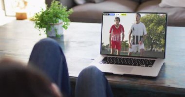 Kanepede oturan ve dizüstü bilgisayarda futbol izleyen bir kadının videosu. Spor, rekabet ve ailece evde vakit geçirmek..