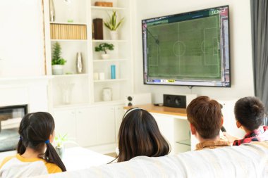 Çeşitli çocuklar birlikte futbol maçı izleyip kanepede oturuyorlar. Futbol, rekabet, tezahürat ve birlikte zaman geçirme..