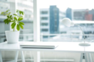 Ofisteki cam pencereye karşı masada elektrikli lambayla dizüstü bilgisayar.