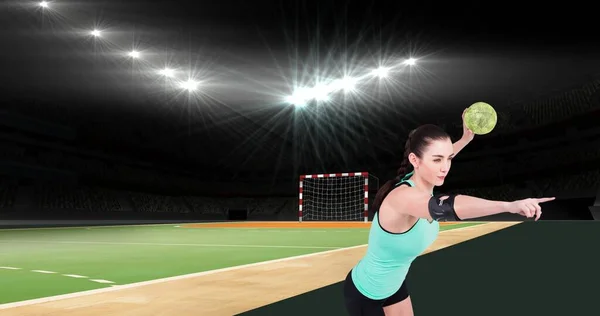 Young caucasian female handball player pointing while playing at illuminated stadium. Copy space, team sport, ball sport, competition, world championship, determination.