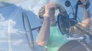 Bisiklete binen engelli beyaz adamın üzerindeki bulutlarla gökyüzünün animasyonu. Uluslararası Engelliler Günü konsepti dijital olarak oluşturulmuş video.