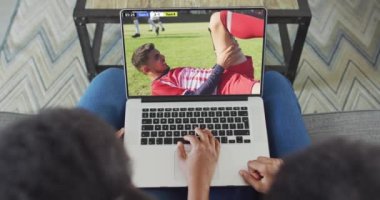 Afro-Amerikan çiftin kanepede oturup dizüstü bilgisayardan futbol izlediği bir video. Spor, rekabet ve ailece evde vakit geçirmek..
