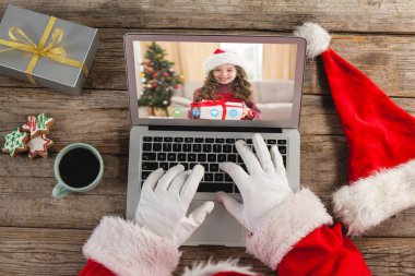 Noel Baba dizüstü bilgisayarda beyaz bir kızın hediyesiyle Noel videosu çekiyor. Noel, şenlik ve iletişim teknolojisi.
