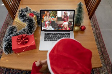 Kafkasyalı bir kadın, Kafkasyalı bir arkadaş grubuyla yılbaşı dizüstü bilgisayarında görüntülü görüşme yapıyor. Noel, şenlik ve iletişim teknolojisi.