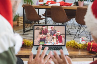 Noel Baba şapkalı beyaz bir baba ve oğul gülümseyen bir aileyle Noel bilgisayarında görüntülü görüşme yapıyor. Noel, şenlik ve iletişim teknolojisi.