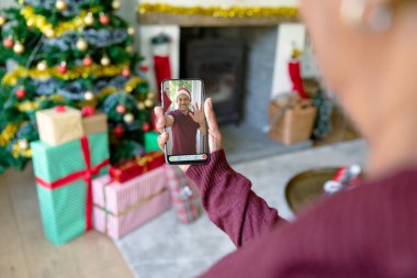 Noel 'de Noel Baba şapkalı melez bir adamla telefon görüşmesi yapan bir kadın. Noel, şenlik ve iletişim teknolojisi.