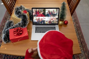 Noel Baba şapkalı, laptoptaki beyaz kadın gülümseyen arkadaşlarıyla Noel videosu görüşmesi yapıyor. Noel, şenlik ve iletişim teknolojisi.