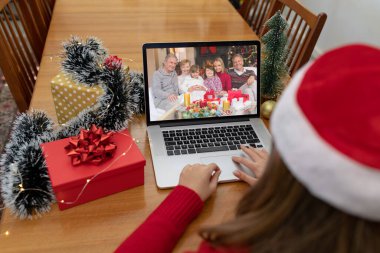 Kafkasyalı bir kadın, Kafkasyalı bir aileyle yılbaşı dizüstü bilgisayarında video görüşmesi yapıyor. Noel, şenlik ve iletişim teknolojisi.