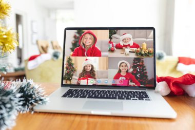 Noel Baba şapkalı mutlu beyaz kızlar dizüstü bilgisayar grubunda gülümsüyor Noel zamanı ekranda ekranı arıyor. Noel, şenlik ve iletişim teknolojisi.