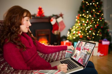 Noel'de evde oturma odasında dizüstü kullanarak içerik Kızıl saçlı