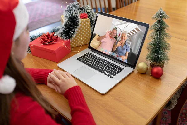 戴着圣诞礼帽的白人妇女与挥手的老夫妇一起制作圣诞手提电脑视频通话 圣诞节 节日和通信技术 — 图库照片