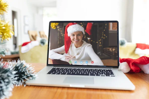 ラップトップのクリスマスビデオ通話インターフェイス画面上のサンタの帽子で笑顔白人女性 クリスマスやお祭りや通信技術は — ストック写真