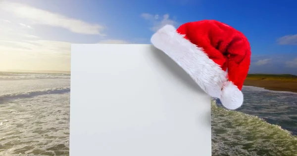 サンタ帽子白カードと海のデジタル合成 — ストック写真
