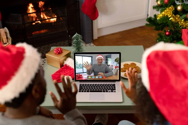クリスマスのビデオ通話でサンタの帽子のアフリカ系アメリカ人のカップルは シニア男性の友人と クリスマスやお祭りや通信技術は — ストック写真