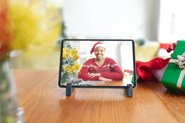 タブレットのビデオ通話画面でサンタの帽子でアフリカ系アメリカ人の女性を笑顔クリスマス クリスマスやお祭りや通信技術は — ストック写真