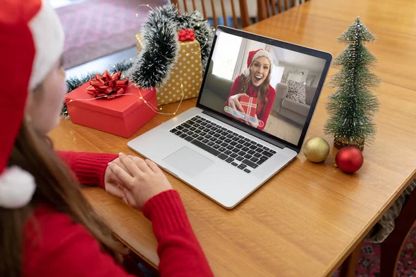 サンタの帽子の白人女性は笑う女性の友人とクリスマスのラップトップビデオ通話を作る クリスマスやお祭りや通信技術は — ストック写真