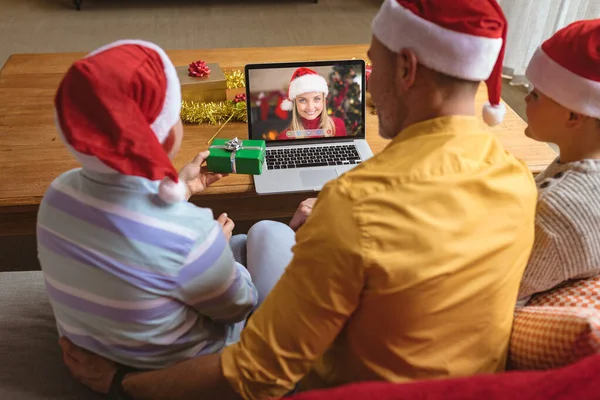 サンタの帽子の白人の父と息子は ラップトップのクリスマスビデオ通話を笑顔の女性と作ります クリスマスやお祭りや通信技術は — ストック写真