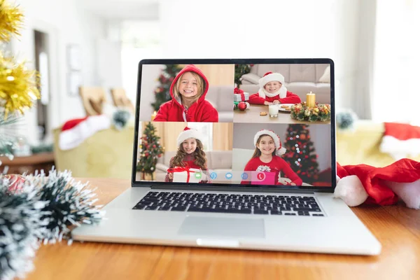 クリスマスの時間にラップトップのグループビデオ通話画面で笑顔サンタの帽子の幸せな白人の女の子 クリスマスやお祭りや通信技術は — ストック写真