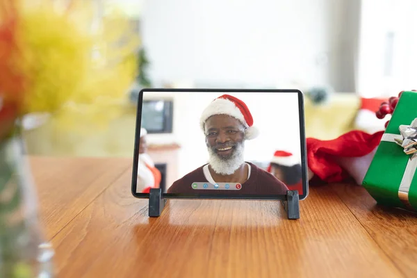 タブレットクリスマスビデオ通話インターフェース画面上のサンタの帽子で笑顔のシニアアフリカ系アメリカ人男性 クリスマスやお祭りや通信技術は — ストック写真
