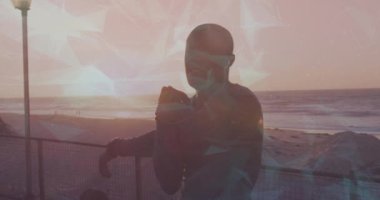 Sahilde gerinen Afrikalı Amerikalı adamın üzerinde hareketli şekillerin animasyonu. sağlık ve zindelik kavramı dijital olarak oluşturulmuş video.