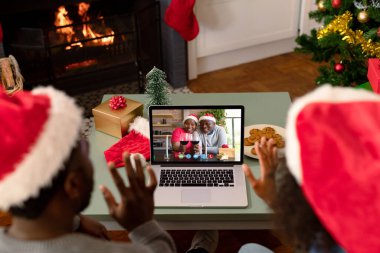 Noel Baba şapkalı Afro-Amerikalı çift, Noel 'de arkadaşlarıyla görüntülü görüşme yapıyor. Noel, şenlik ve iletişim teknolojisi.