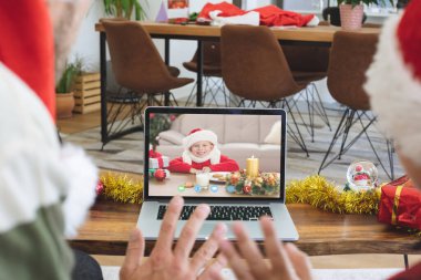 Baba ve kızını gülümseyen beyaz bir kızla dizüstü bilgisayardan Noel videosu çekiyorlar. Noel, şenlik ve iletişim teknolojisi.