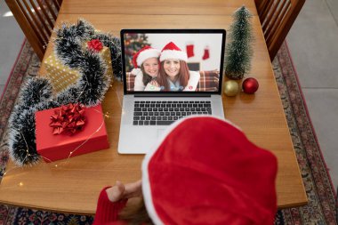 Kafkasyalı bir kadın, Kafkasyalı bir anne ve kızıyla yılbaşı dizüstü bilgisayarında video görüşmesi yapıyor. Noel, şenlik ve iletişim teknolojisi.