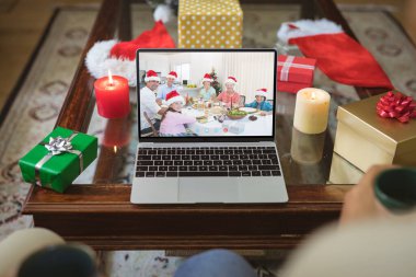 Bilgisayarlı Noel Baba şapkalı, çok nesildir gülümseyen beyaz bir aile. Noel, şenlik ve iletişim teknolojisi.